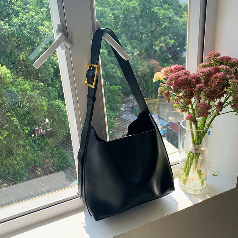 Sac Margot noir près d’une fenêtre, boucle dorée visible