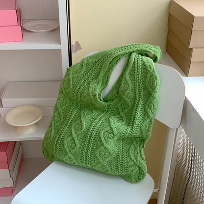 Cabas Juliette vert en maille torsadée posé sur une chaise