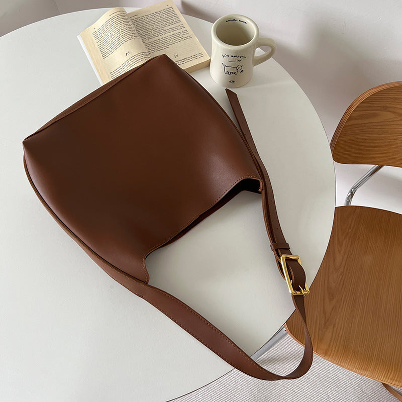 Sac Margot marron posé sur une table, matière lisse et bandoulière visibles