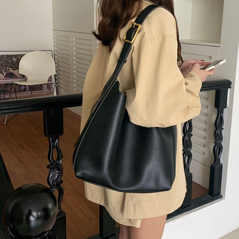 Sac Margot noir porté à l’épaule avec une tenue beige