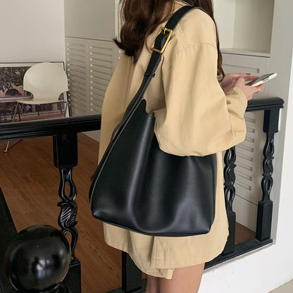 Sac Margot noir porté à l’épaule avec une tenue beige